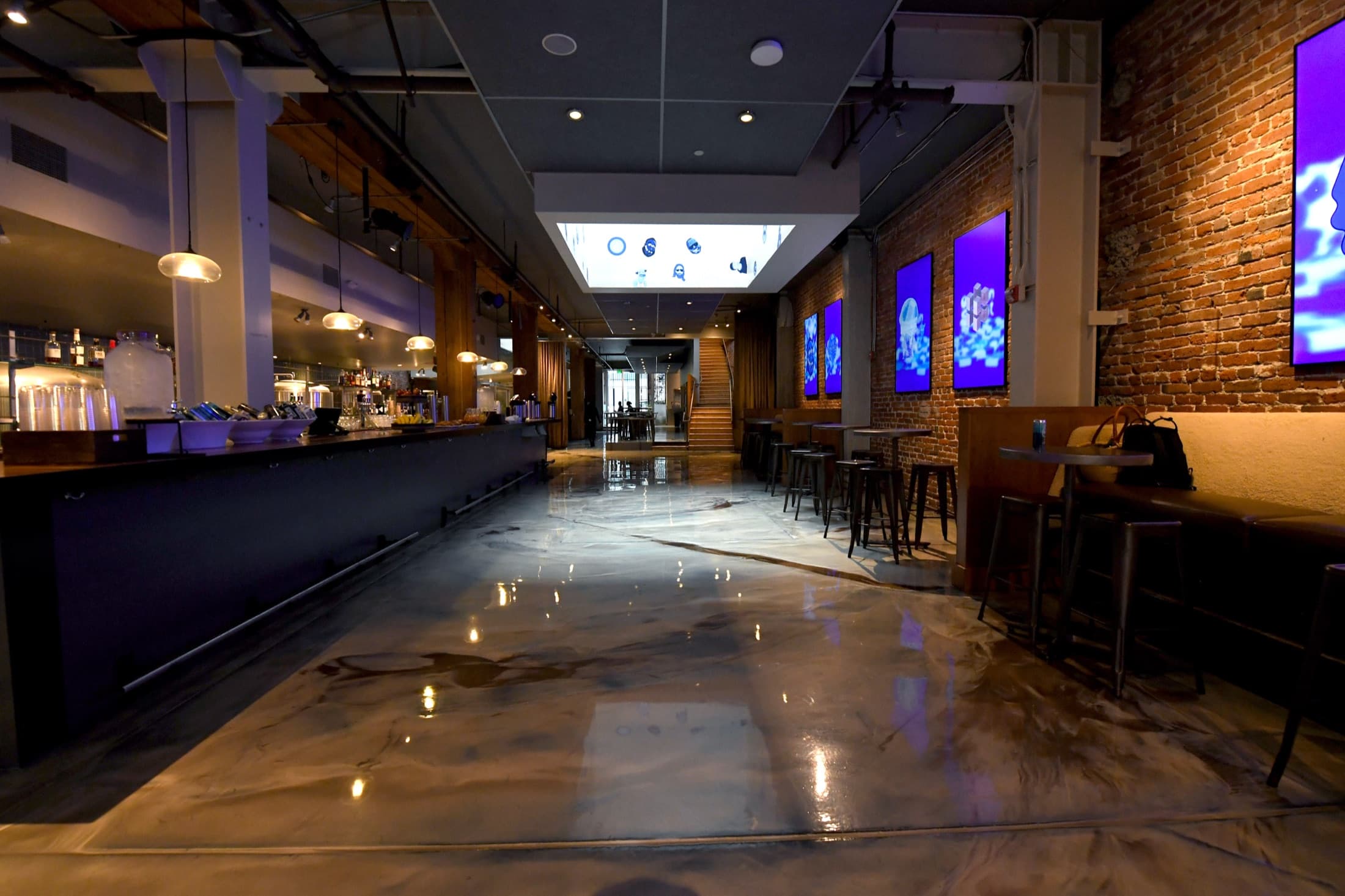 Large-scale takeover venue interior with exposed brick, bar, and digital wall displays